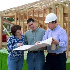 Image of couple with building plans with contractor in front of new construction