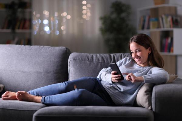 Woman sitting on couch looking at cell phone